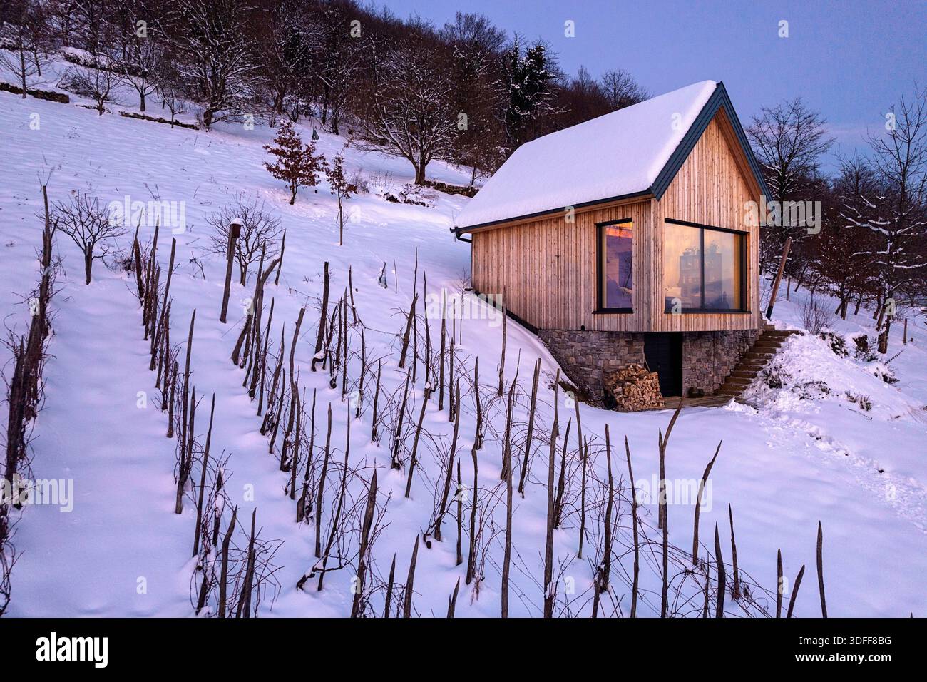 serata invernale nel paesaggio rurale. il paesaggio delle favole invernali con una piccola cabina illuminata in legno ricoperta di neve Foto Stock
