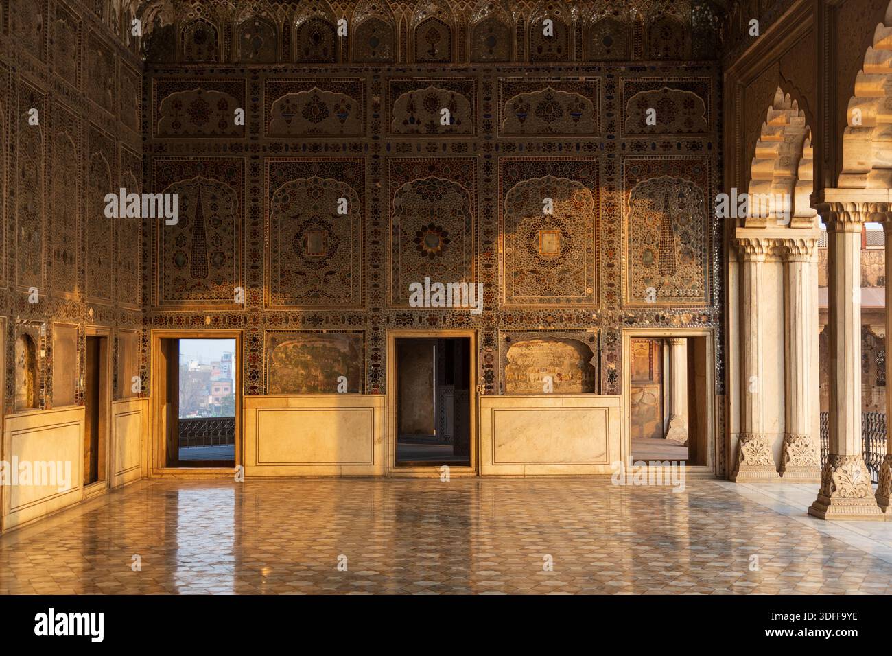 Vista della sala decorata e illuminata dal sole con le sue intricate pareti e archi intagliati, che riflettono la luce sul pavimento lucido, Lahore, Punjab, Pakistan. Foto Stock