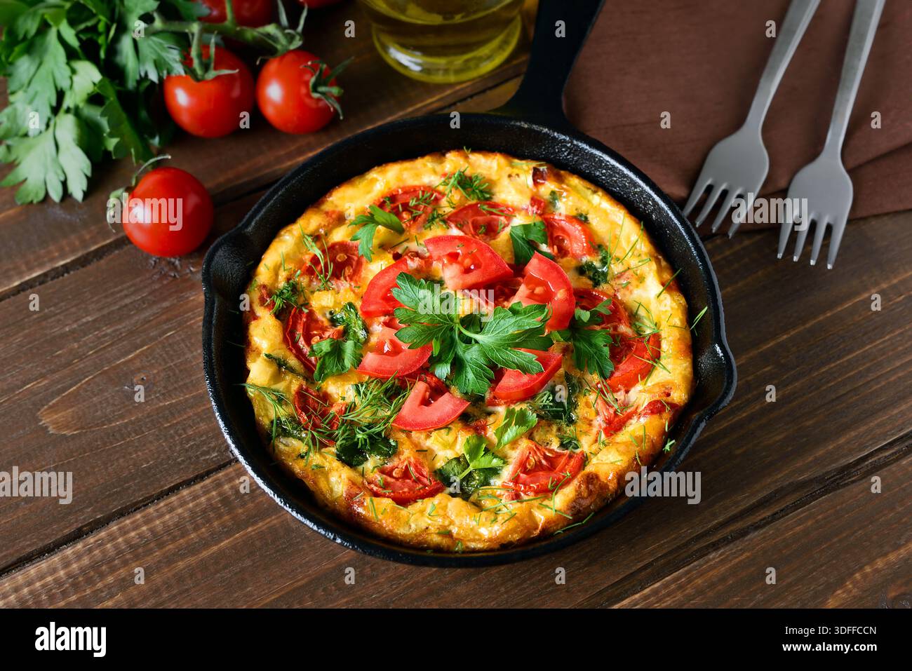 Frittata con pomodori e spinaci in padella Foto Stock