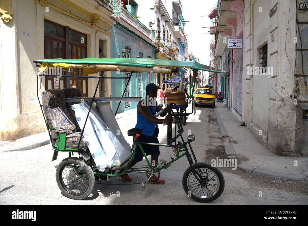 Pedala trasportando oggetti domestici lungo una strada stretta nella vecchia Avana, Cuba Foto Stock