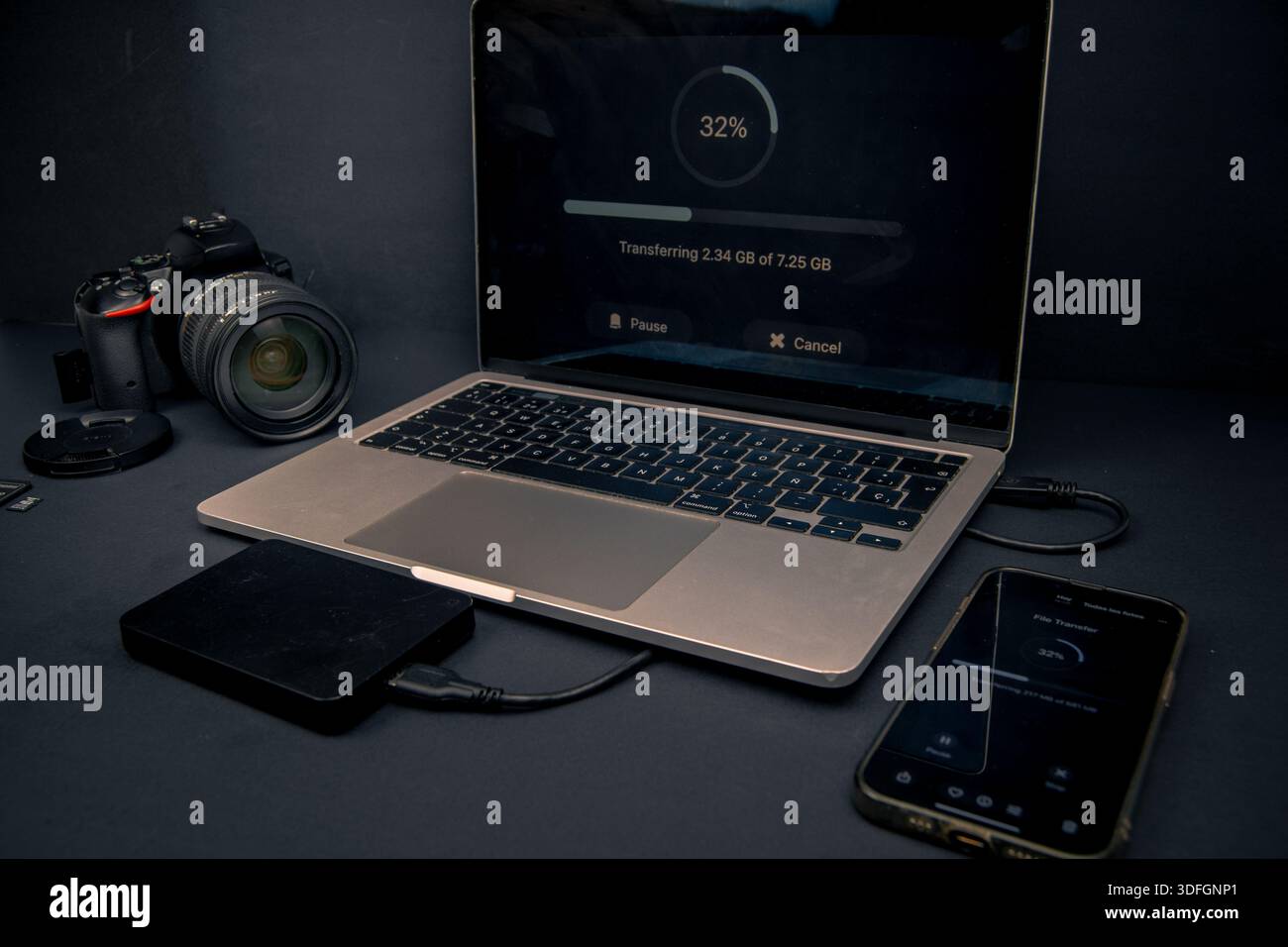 Laptop e smartphone che mostrano l'avanzamento del trasferimento di file con una fotocamera e un disco rigido esterno. Flusso di lavoro di backup, archiviazione e gestione dei dati. Foto Stock