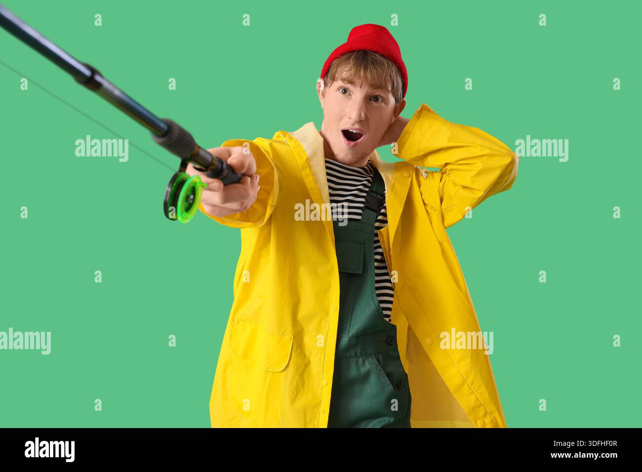 Giovane divertente con canna da pesca su sfondo verde Foto Stock