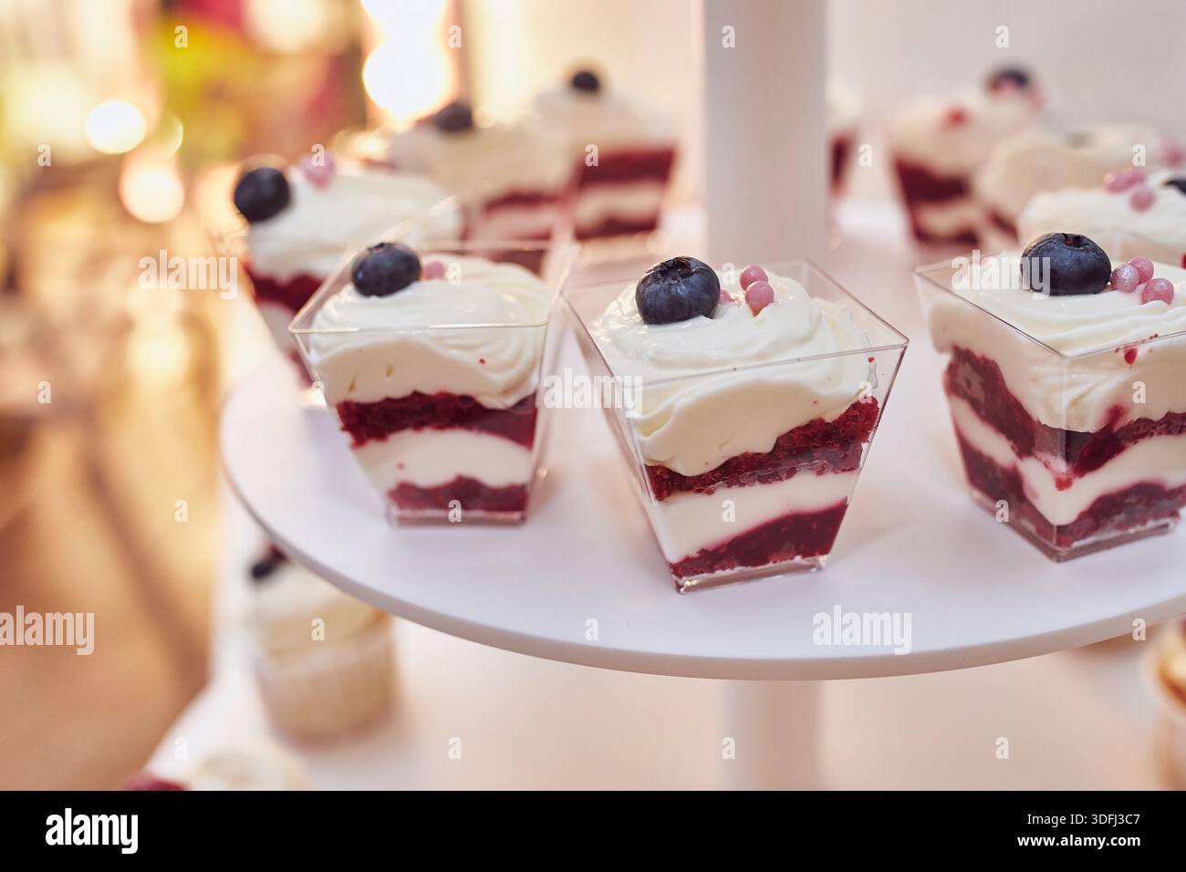 Dessert in porzioni con panna e frutti di bosco sul tavolo delle feste Foto Stock