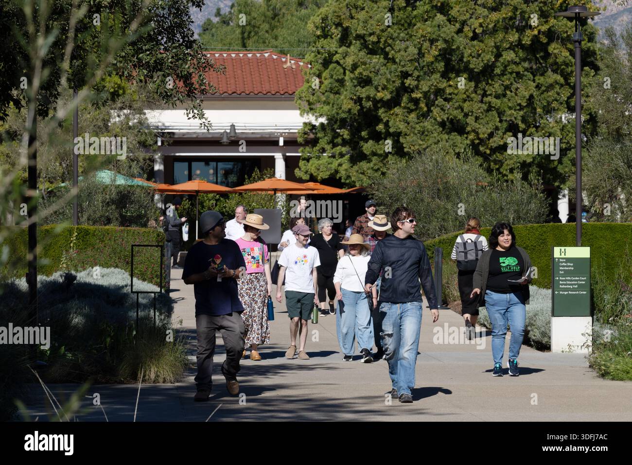 I visitatori camminano lungo un sentiero principale vicino a un edificio con giardino ai giardini botanici di Huntington a Pasadena, California, Stati Uniti. Foto Stock