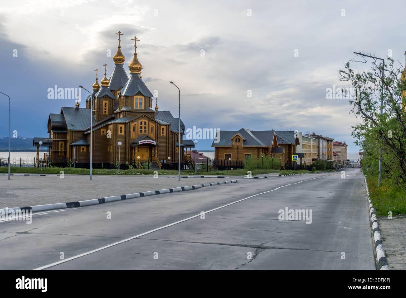 Cattedrale della Santissima Trinità ad Anadyr, Chukotka, Russia, chiesa ortodossa in legno con cupole dorate che si affaccia sulla strada e sulla baia sotto il cielo nuvoloso. Foto Stock