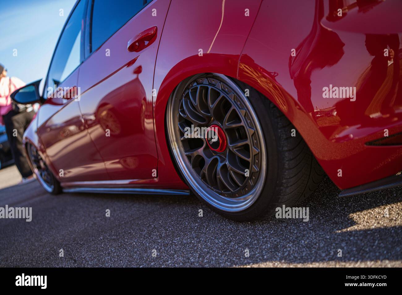 Imola, italia 01 gennaio 2026: Auto personalizzata rossa che mostra il suo profilo basso, ruota aftermarket con bordo profondo e riflesso sull'elegante carrozzeria pa Foto Stock