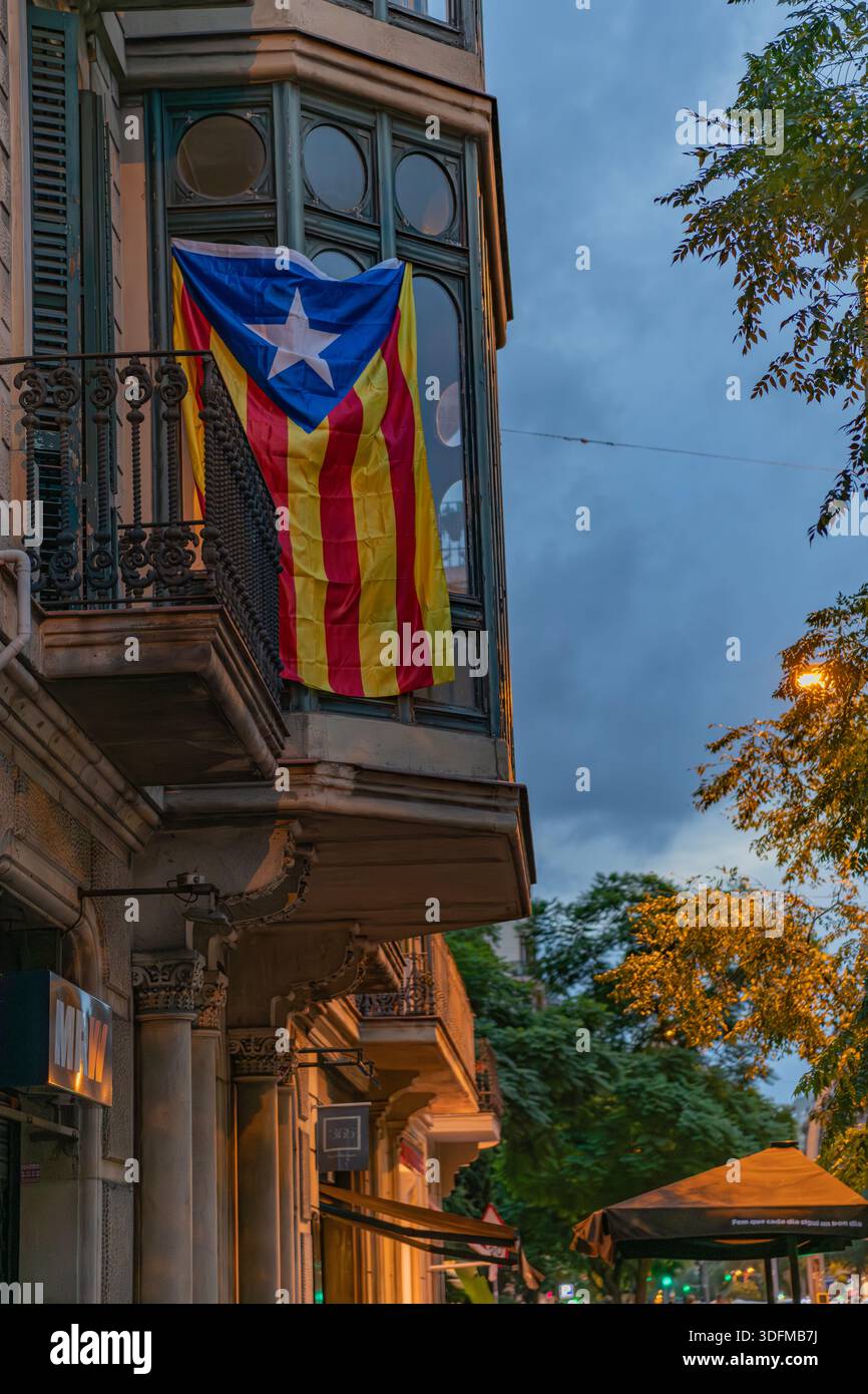Barcellona, Spagna - 20 ottobre 2025: Una bandiera Estelada appesa da un balcone su un edificio residenziale al crepuscolo. Foto Stock