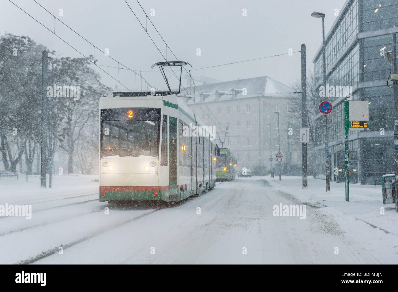 Il tram stradale invernale mostra le forti nevicate dei trasporti pubblici in condizioni di ghiaccio ridotta visibilità. Piste innevate edifici urbani mobilità Foto Stock