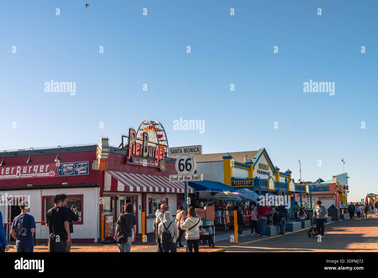 Molo di Santa Monica in California con caffè, ristoranti e turisti, con l'iconico cartello che segna la fine della Route 66. Vivace scena costiera Foto Stock