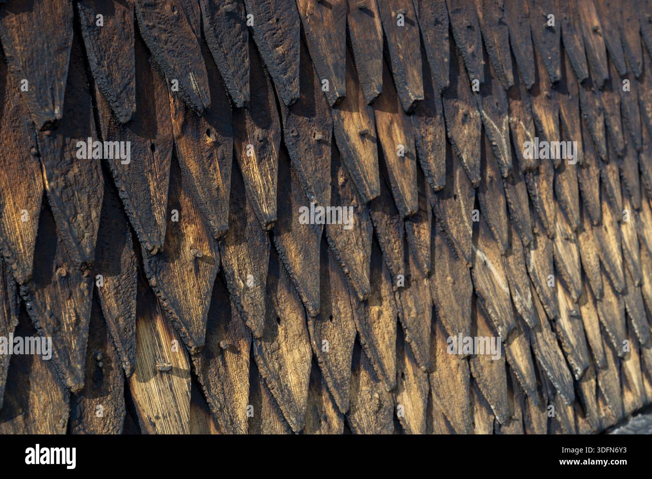 La vista delle scintille di legno sovrapposte agli agenti atmosferici crea un arazzo testurizzato di marrone scuro e neri, che suggerisce l'antica architettura della chiesa della pietra, Eid Foto Stock