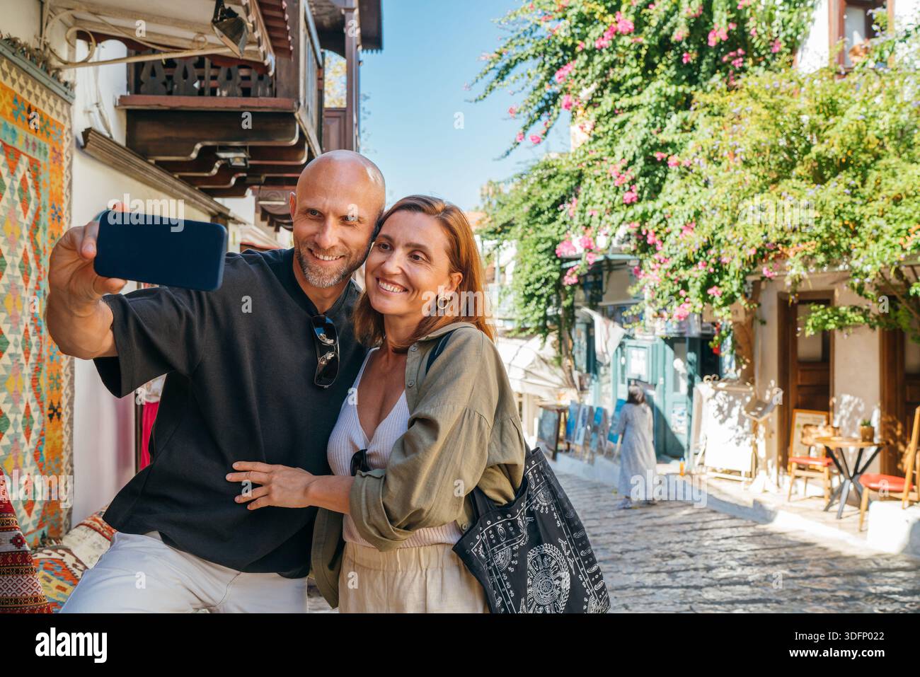 Coppia di mezza età sorridente mentre fai selfie con lo smartphone nella stretta strada del centro storico di Kas. Un romantico rapporto d'amore per i viaggi, Honeymo Foto Stock