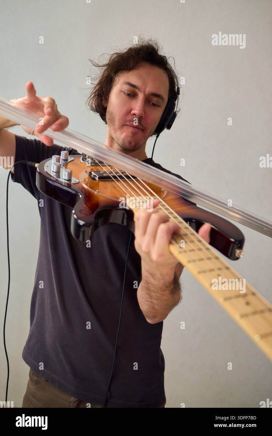 Bassi potenti, prestazioni dinamiche che comunicano con passione attraverso il basso, musicista dai capelli ricci immersi in bassi espressivi Foto Stock