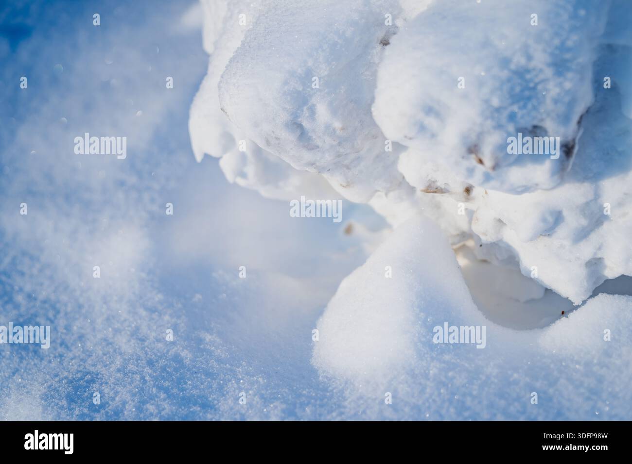 Vista macro della superficie della neve in polvere e dei frammenti di neve arrotondati con piccole macchie di sporco, luce naturale brillante per creare una texture di sfondo astratta e pulita Foto Stock