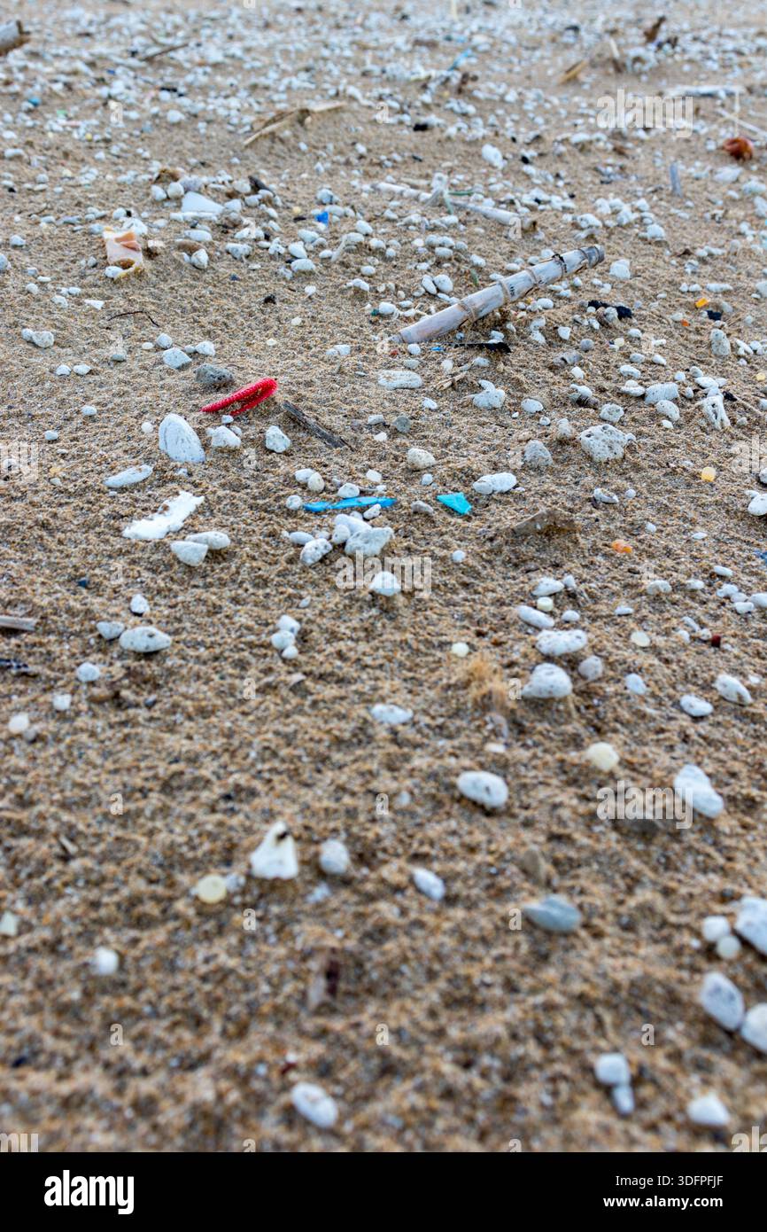 Spiaggia sabbiosa contaminata da microplastiche. Vista ravvicinata di microplastiche e rifiuti su una spiaggia. Foto Stock