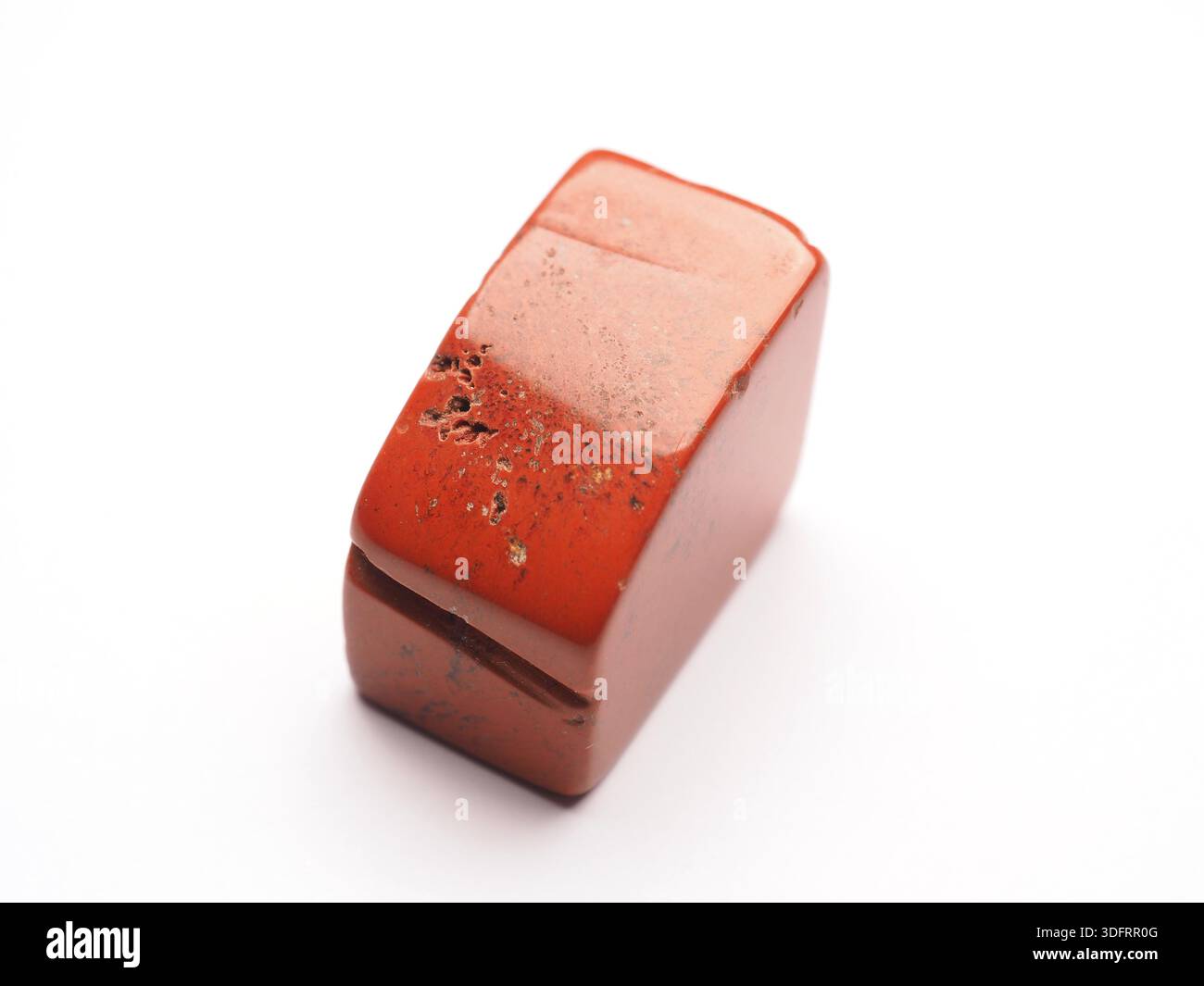 Primo piano di una pietra di guarigione rossa di jasper su sfondo bianco, pietra concettuale di coraggio, forza di volontà e vitalità Foto Stock