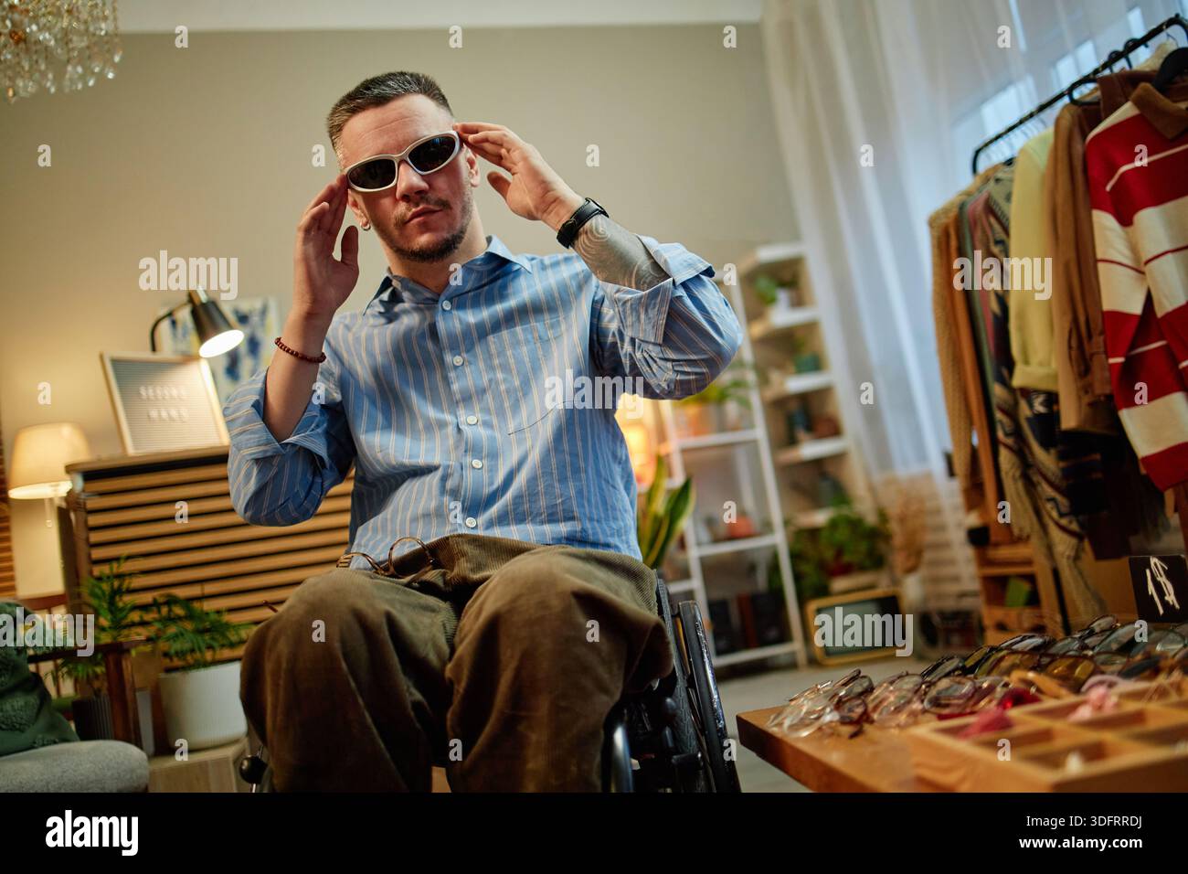 Ritratto di un giovane adulto uomo caucasico con disabilità che prova a fare shopping con gli occhiali da sole Foto Stock