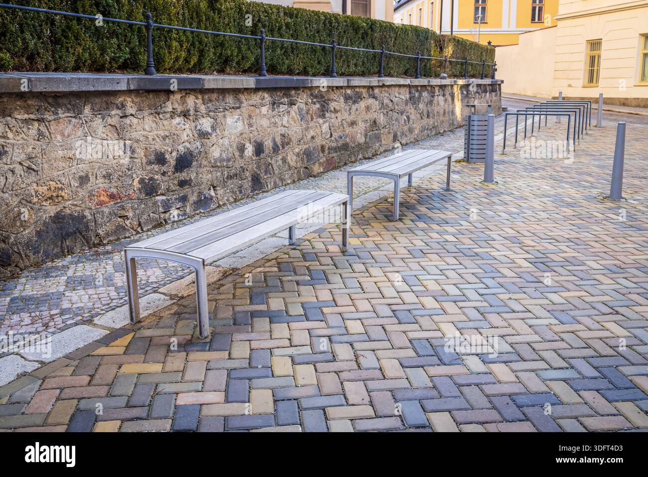 Panchine moderne della città vecchia con pavimentazione in pietra Foto Stock