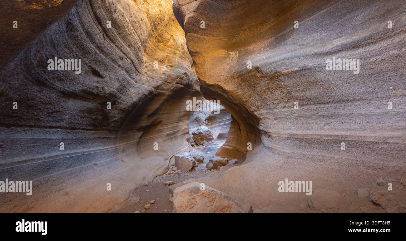 Stretto canyon nel deserto con pareti di roccia curve e stratificate e luce che illumina il percorso Foto Stock
