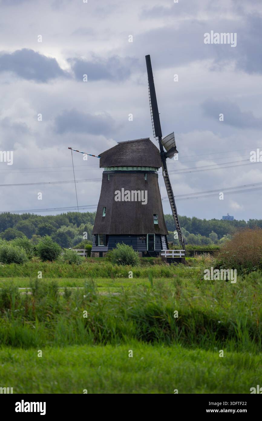 Un mulino a vento nella campagna olandese contro un cielo nuvoloso Foto Stock