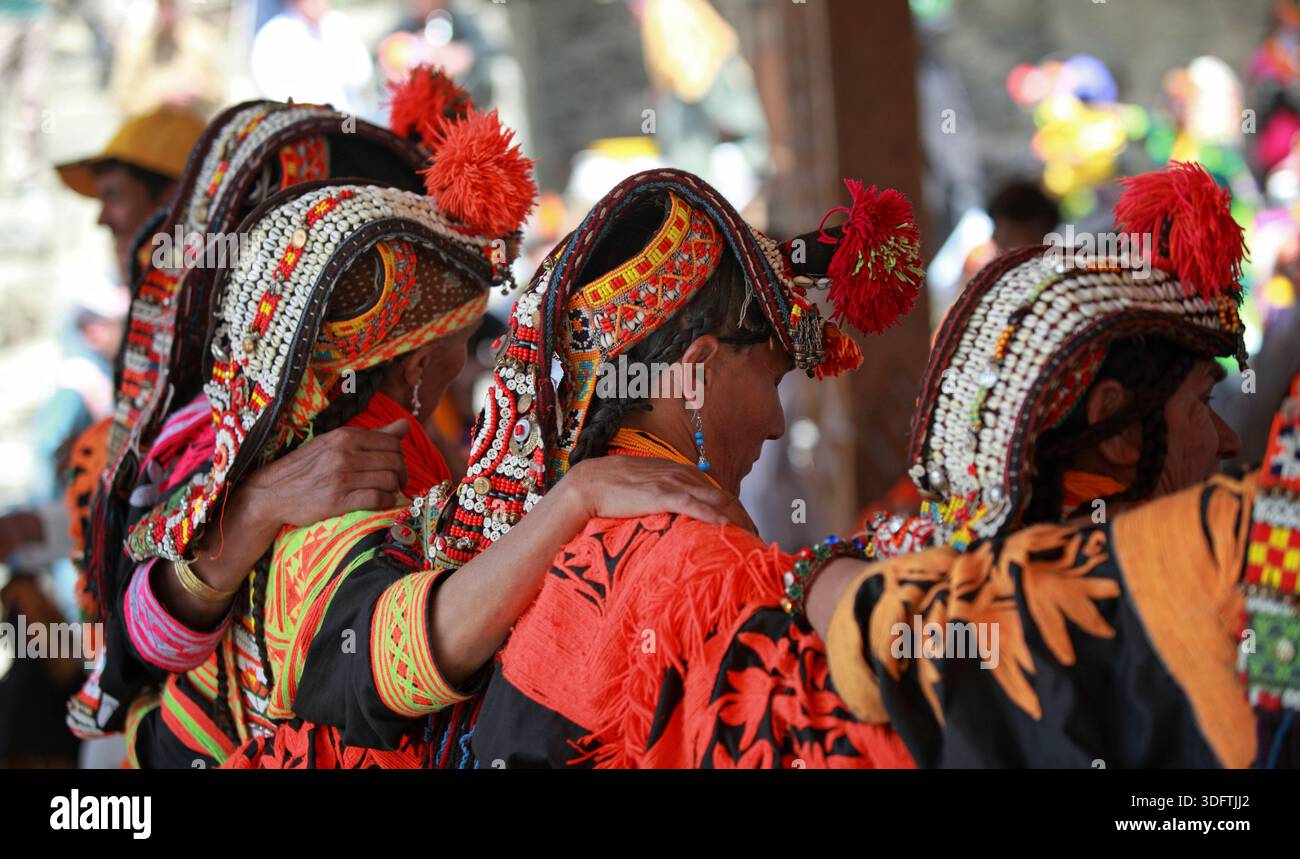 Kalash, Pakistan - 24 dicembre 2025: Veduta delle donne adornate con i tradizionali copricapi Kalash e i vivaci scialli arancioni, il loro intricato shimm Foto Stock