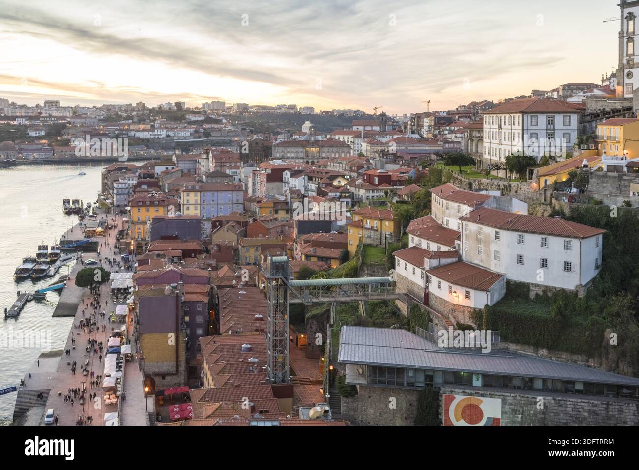 Porto, Portogallo - 26 novembre 2017: Vista dei colorati edifici di Ribeira che scendono fino al fiume Douro sotto un cielo soffice e luminoso, con il Dom Luí Foto Stock