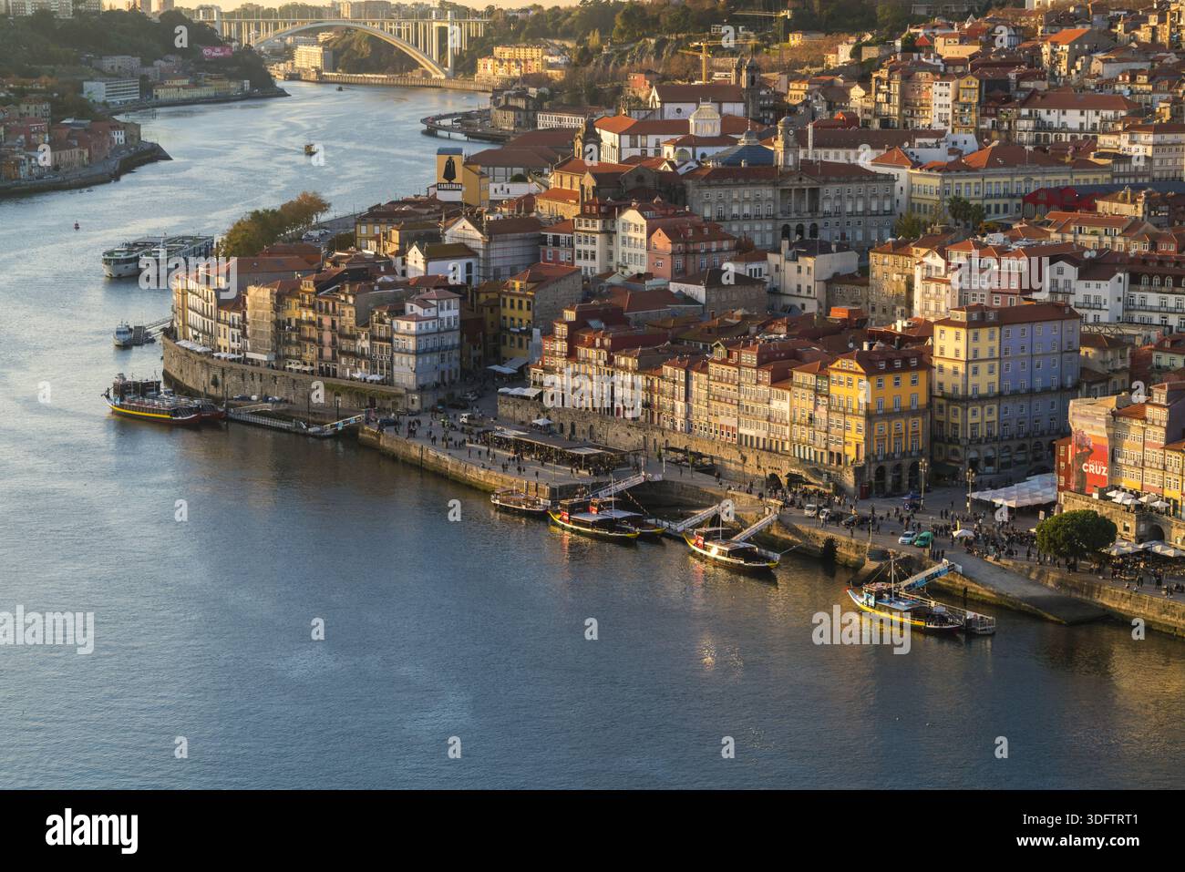 Porto, Portogallo - 26 novembre 2017: Veduta del fiume Douro che riflette la luce dorata del sole che tramonta, illuminando il colore del quartiere di Ribeira Foto Stock