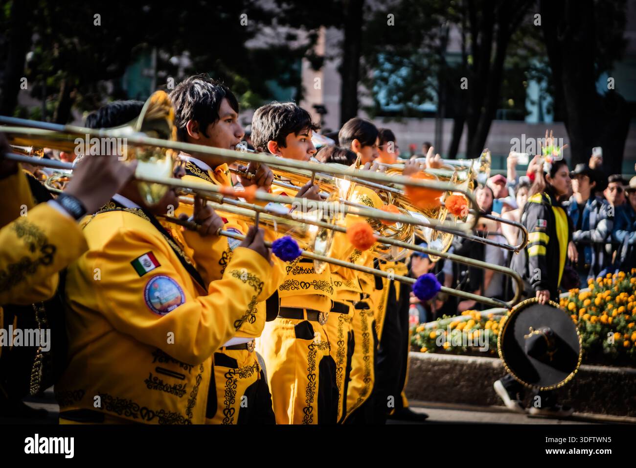 Città del Messico, Messico - 4 novembre 2023: Veduta di una vivace sfilata con musicisti in abiti gialli luminosi che suonano tromboni nella par del giorno della morte Foto Stock