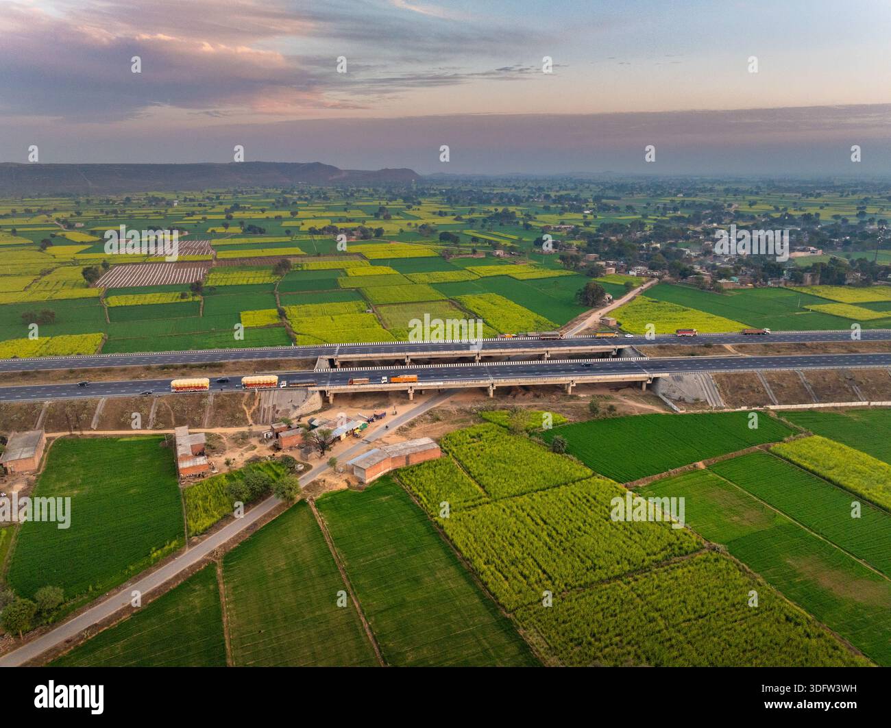 Vista aerea dei vivaci campi di patchwork incontra le linee strutturate delle strade sotto il soffice bagliore del cielo serale, Alwar, Rajasthan, India. Foto Stock