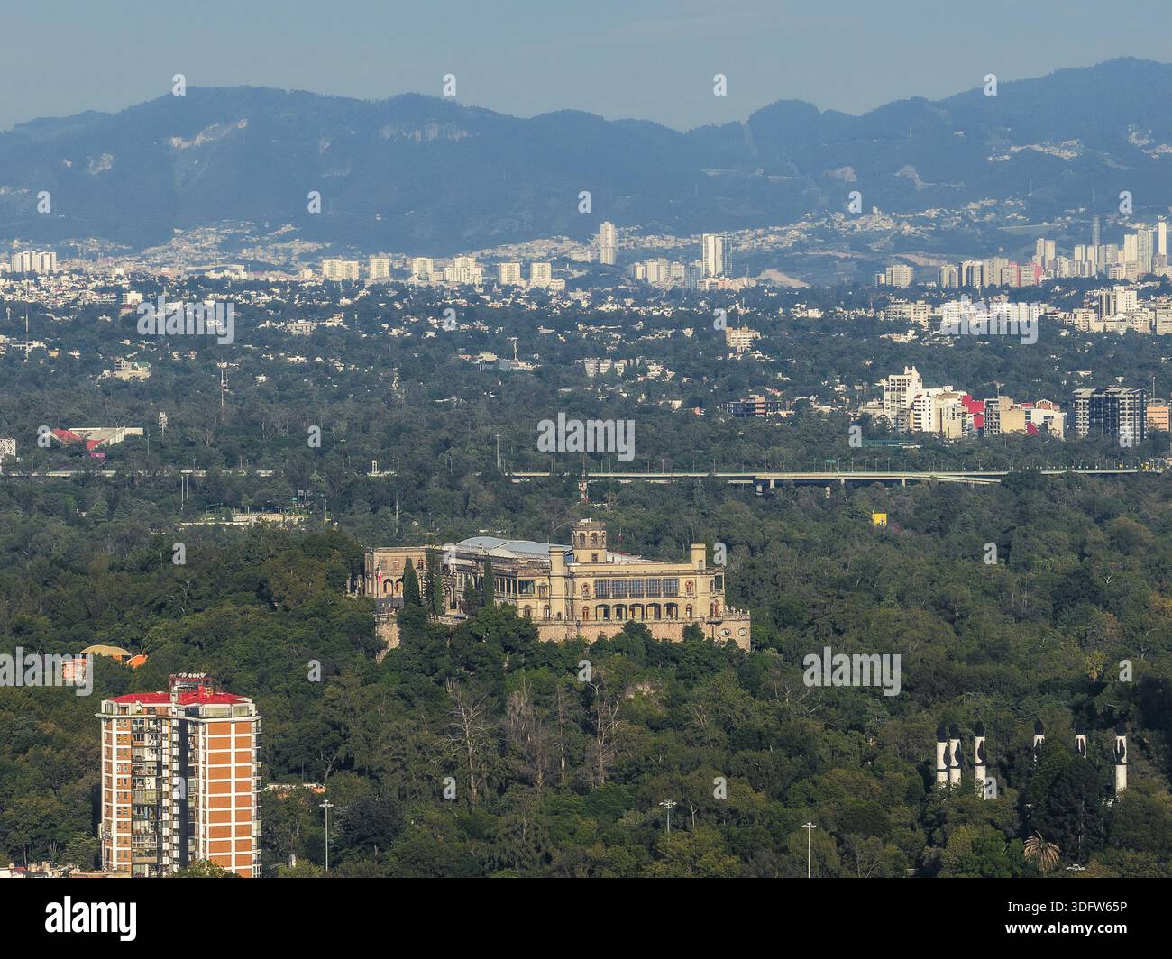 Vista aerea del castello di Chapultepec che incornicia una collina verdeggiante in un vasto paesaggio urbano dipinto in toni tenui, incorniciato da montagne lontane, Messico Cit Foto Stock
