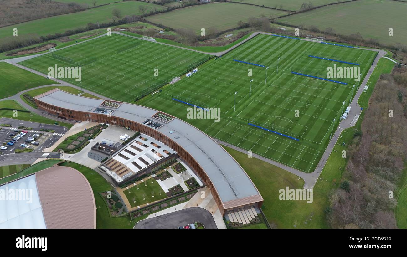 Vista aerea dei campi da calcio verdi a righe adiacenti all'architettura moderna e curva, una sinfonia di linee e forme contro il paesaggio mutevole, Sile Foto Stock