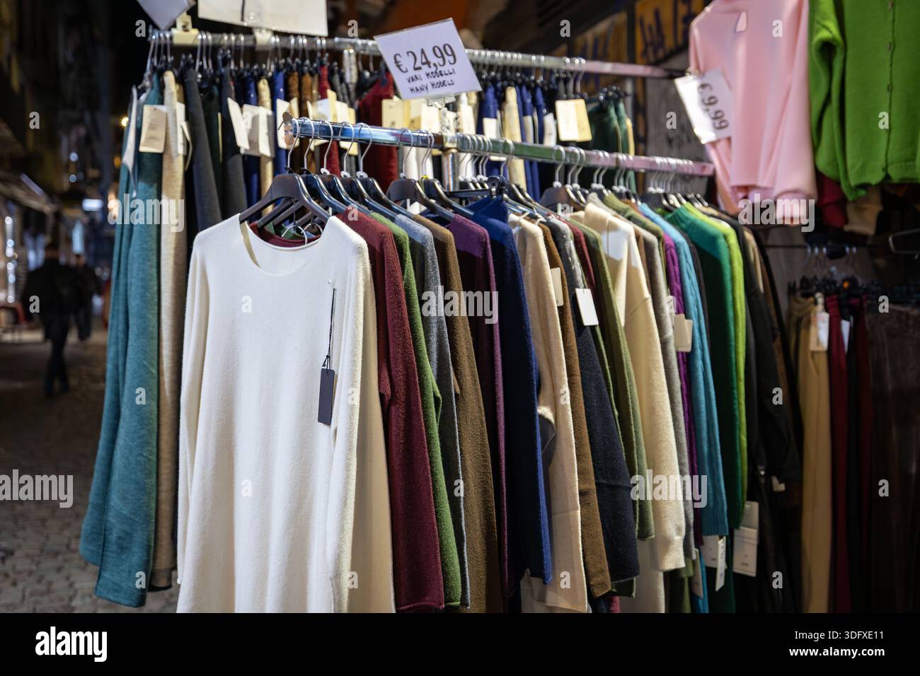 Napoli, Italia - 8 gennaio 2026: Mostra al dettaglio di maglioni e camicie di lana colorate su grucce in un mercato all'aperto in Italia. Prezzo Foto Stock