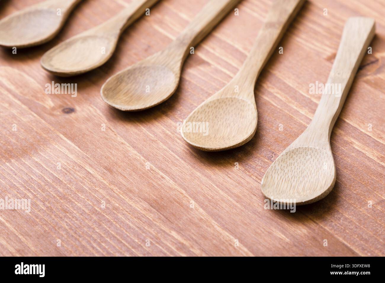 Cinque cucchiai di legno marroni su un tavolo di legno Foto Stock