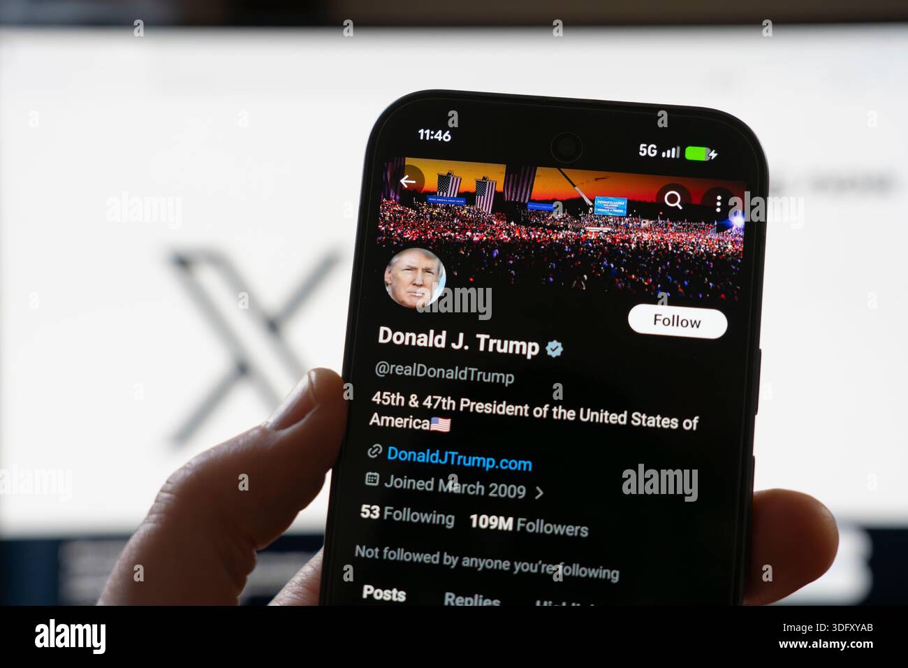 Mano di un uomo che tiene il cellulare con il profilo X di Donald J Trump, presidente degli Stati Uniti e avido utente di social media e poster su X. Foto Stock