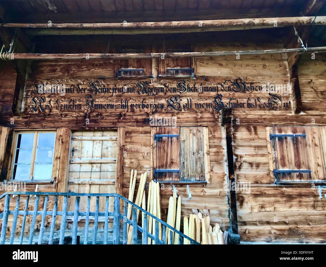 La facciata di un'antica capanna alpina svizzera presenta legno scuro e intemprato, tradizionali persiane alle finestre e robuste ringhiere in legno, l'Oberland Bernese Foto Stock