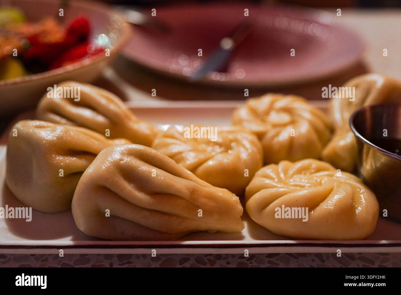 Piatto tradizionale georgiano khinkali servito su un piatto sotto una calda luce gialla. Gnocchi fatti in casa che mostrano autentica cucina e cultura georgiana. Foto Stock
