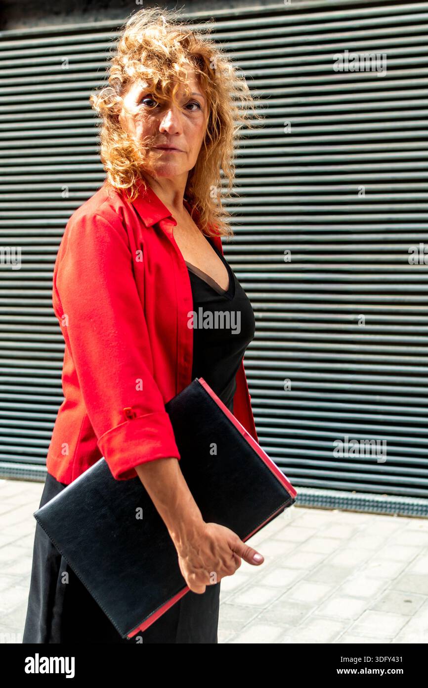 Donna matura e sicura che cammina in città con i documenti in mano Foto Stock