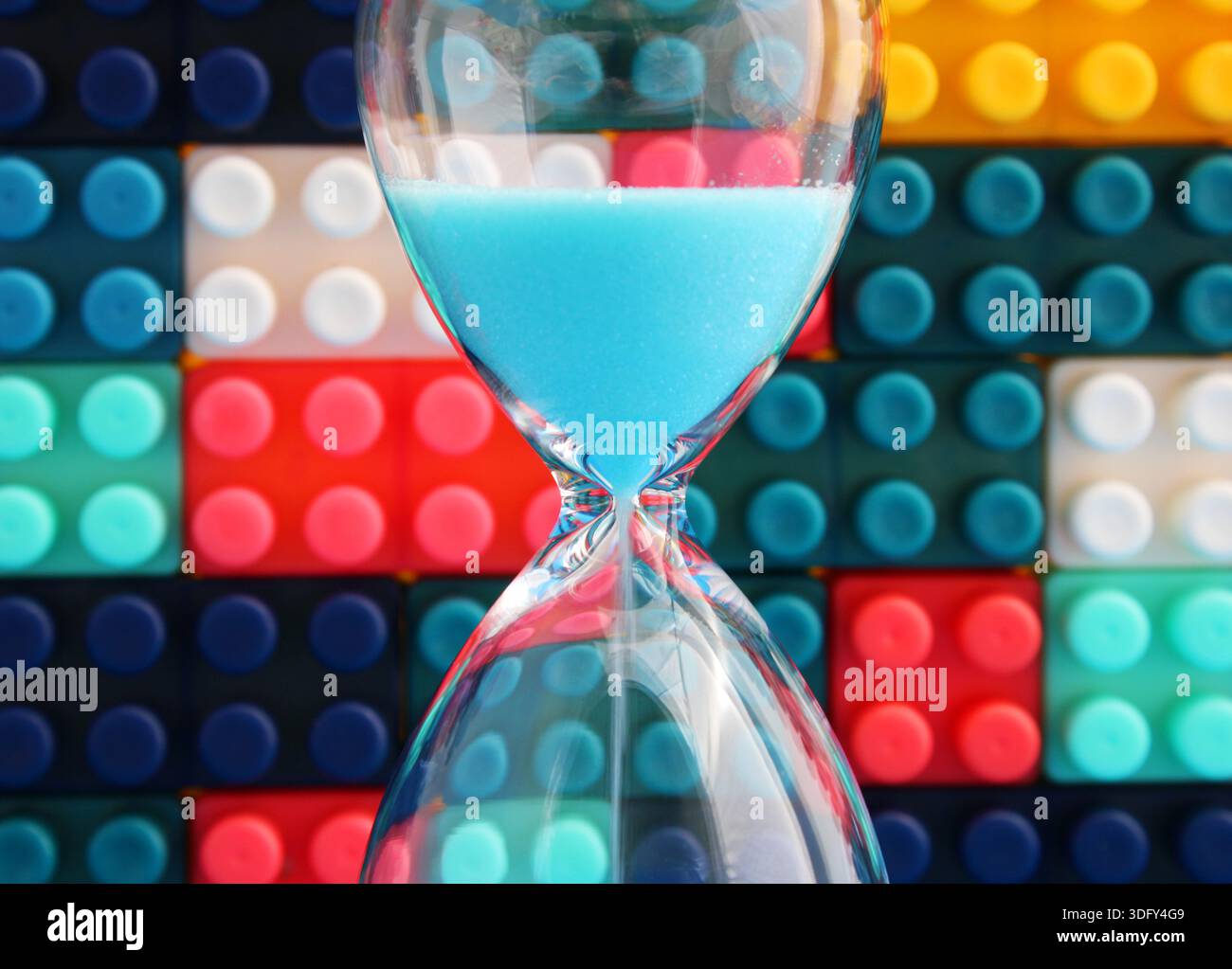 Clessidra con pezzi colorati di puzzle sullo sfondo Foto Stock