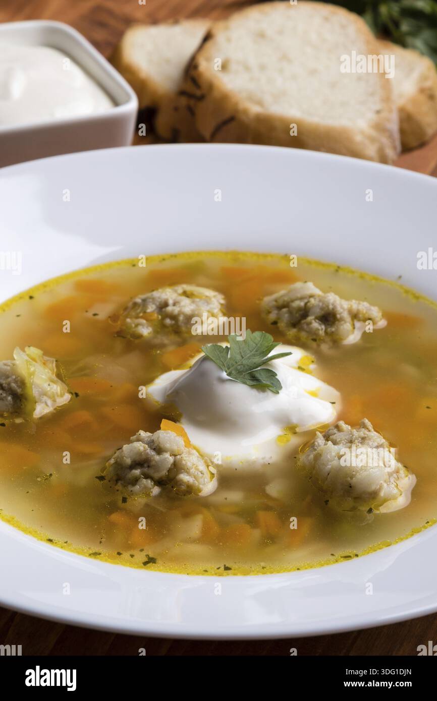 Zuppa di verdure e polpette su un tavolo di legno in piatto bianco Foto Stock