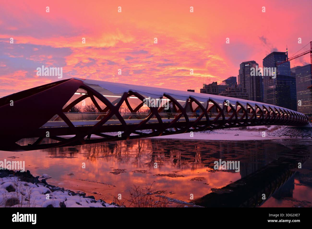 Un'alba si illumina nel cielo sopra lo skyline di Calgary Alberta e il Peace Bridge in una mattina d'inverno Foto Stock