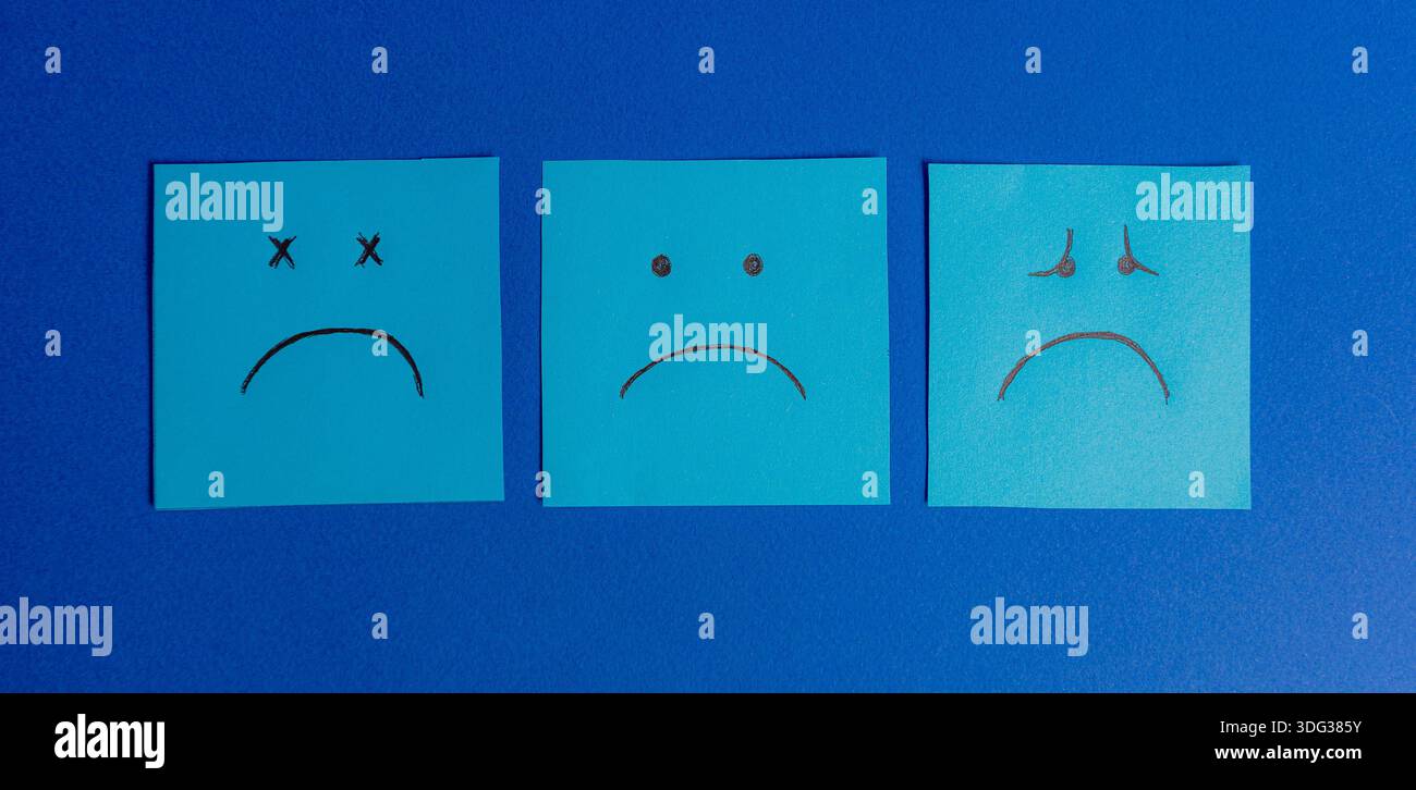 Tre note adesive quadrate disposte in fila su sfondo blu, che mostrano diverse espressioni di tristezza, stanchezza e depressione. Foto Stock