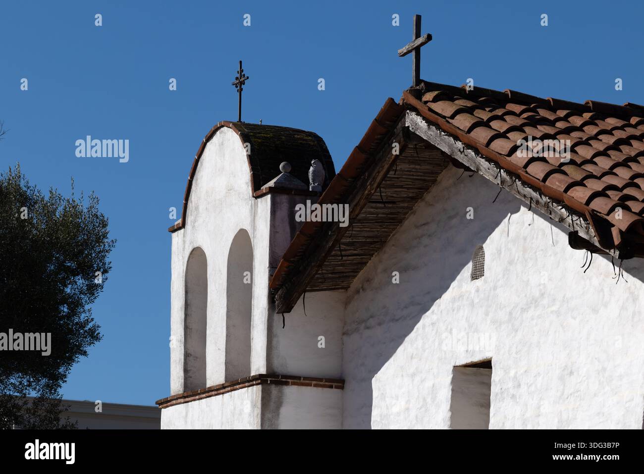 Campanile in stucco bianco e tetto piastrellato con croci sagomate su un cielo azzurro cristallino all'El Presidio di Santa Barbara, California, Stati Uniti. Foto Stock