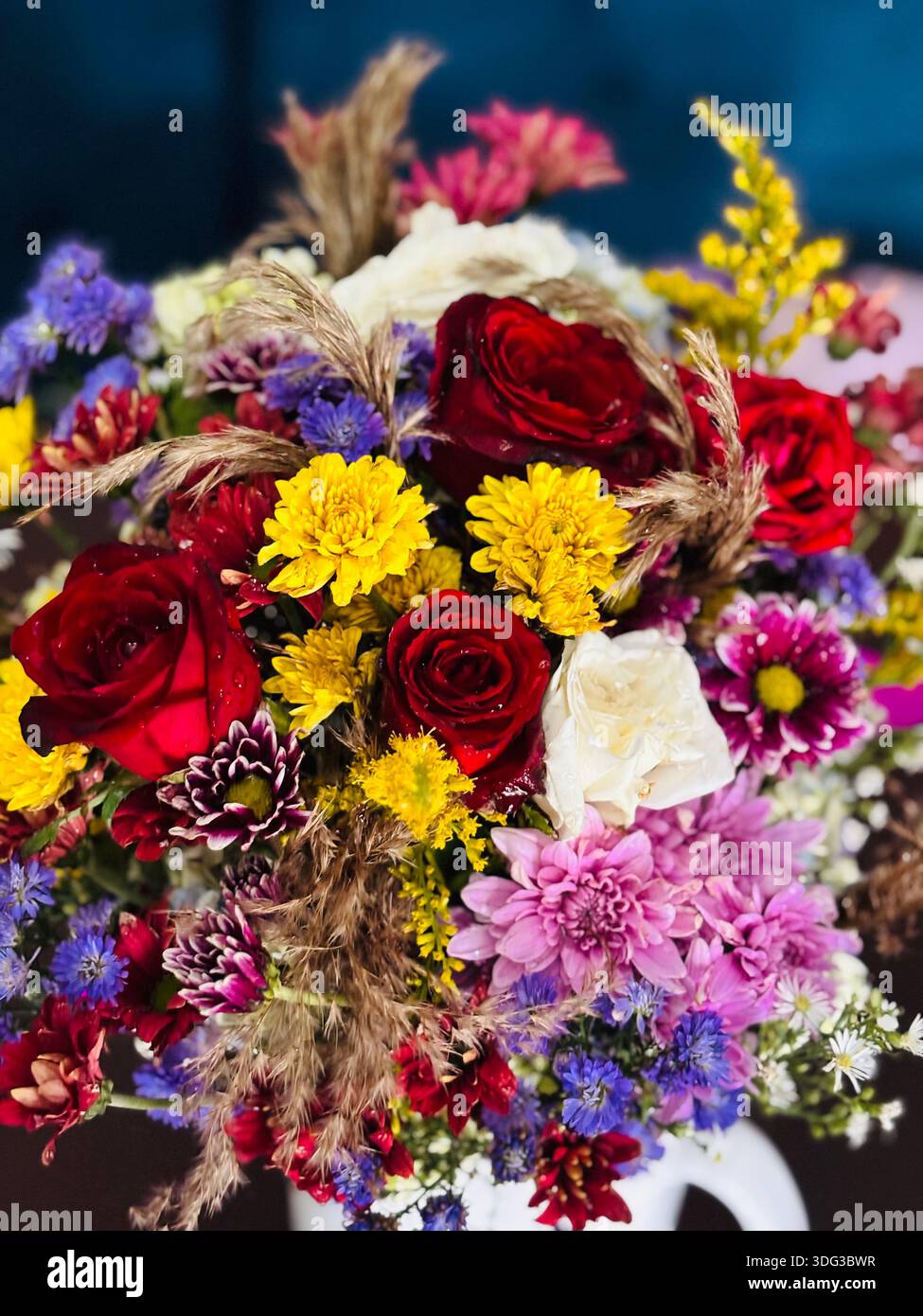 Vivace bouquet di fiori misti con rose rosse, crisantemi e fiori selvatici disposti in un'esposizione floreale decorativa. Petali freschi con acqua visibile - Immagine stock catturata con smartphone