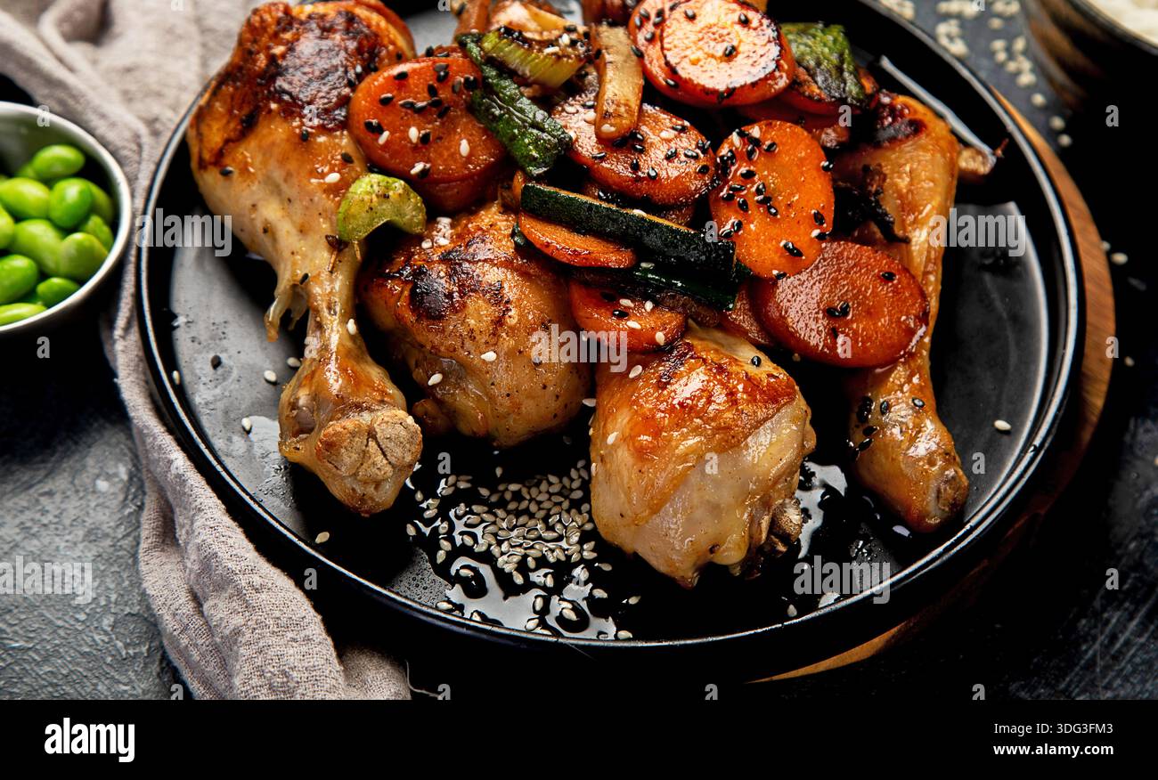 Ali di pollo con glassa dolce e salata servita con riso e funghi su sfondo scuro. Vista dall'alto. Foto Stock