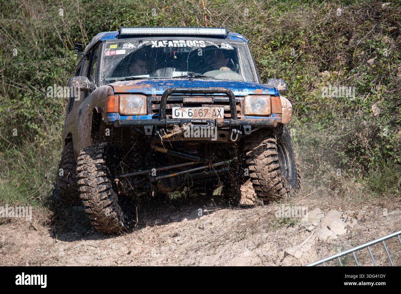 Vista anteriore di una Land Rover Discovery blu modificata che mostra un'articolazione estrema delle sospensioni. Fangoso 4x4 con verricello e barra luminosa che navigano su una bocca robusta Foto Stock