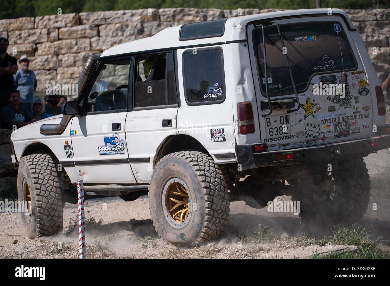 Vista posteriore di una Land Rover Discovery serie i bianca modificata che corre su una pista sterrata. Azione ad alta velocità con nuvole di polvere, decalcomanie da corsa e di Foto Stock
