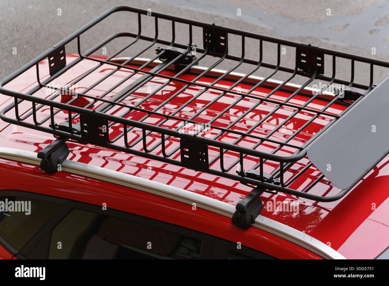 Portapacchi nero montato su un'auto rossa per trasportare bagagli extra Foto Stock