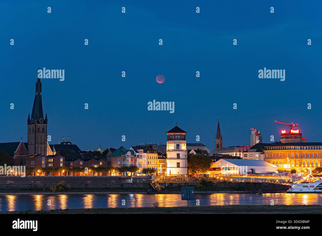 Una luna di sangue scintillante sale sulla città vecchia di Düsseldorf e sul lungomare del Reno, dando vita a una magica scena notturna Foto Stock