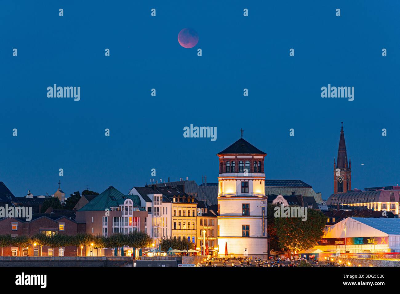 Una luna di sangue scintillante sale sulla città vecchia di Düsseldorf e sul lungomare del Reno, dando vita a una magica scena notturna Foto Stock
