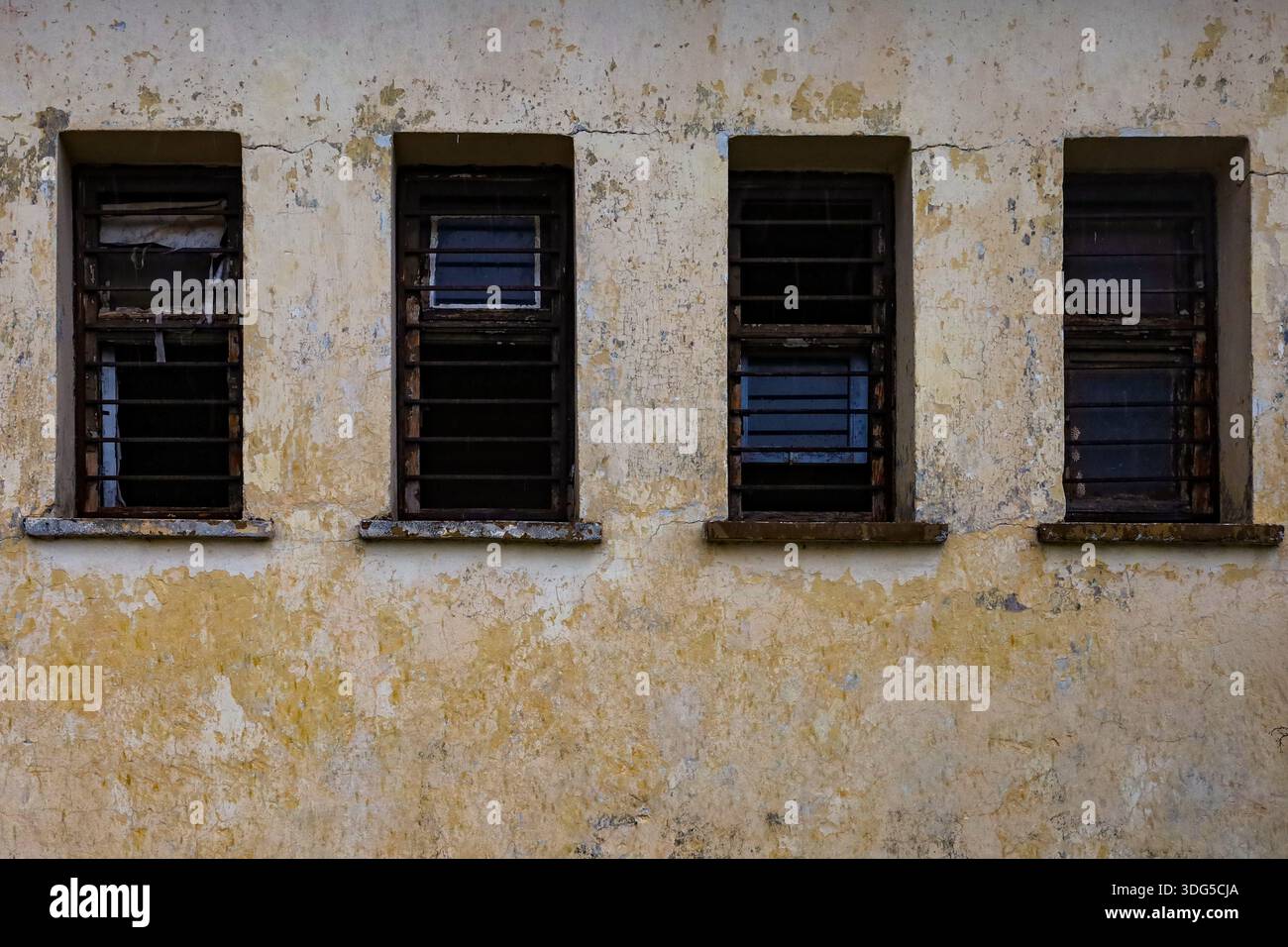 Sbarrate e rotte, queste finestre di un'ex struttura militare simboleggiano il confinamento, il decadimento e la perdita di autorità. Foto Stock