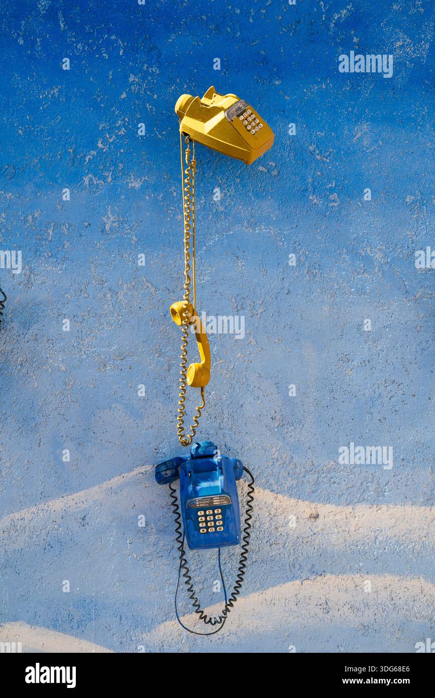 Telefoni vintage gialli e blu su una parete testurizzata e dipinta di blu. Ouarzazate, Marocco Foto Stock